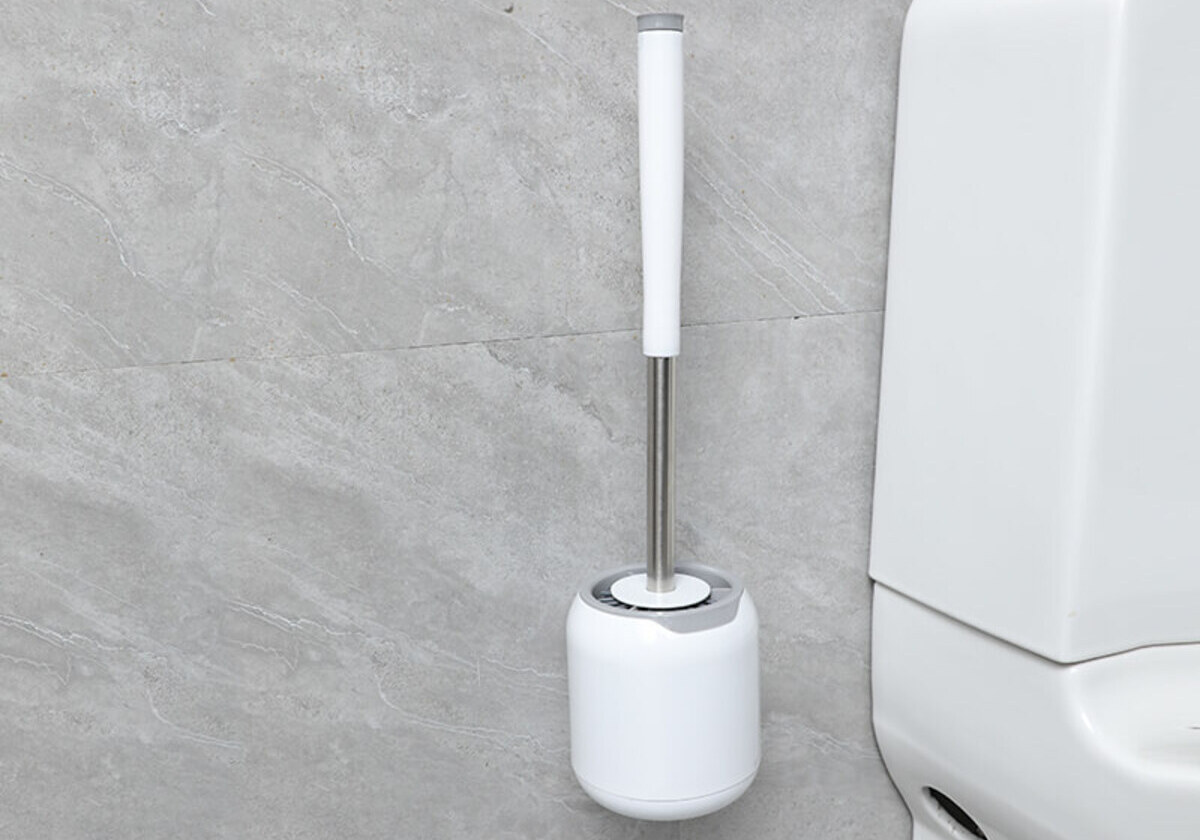 A white wall-mounted toilet brush with a holder