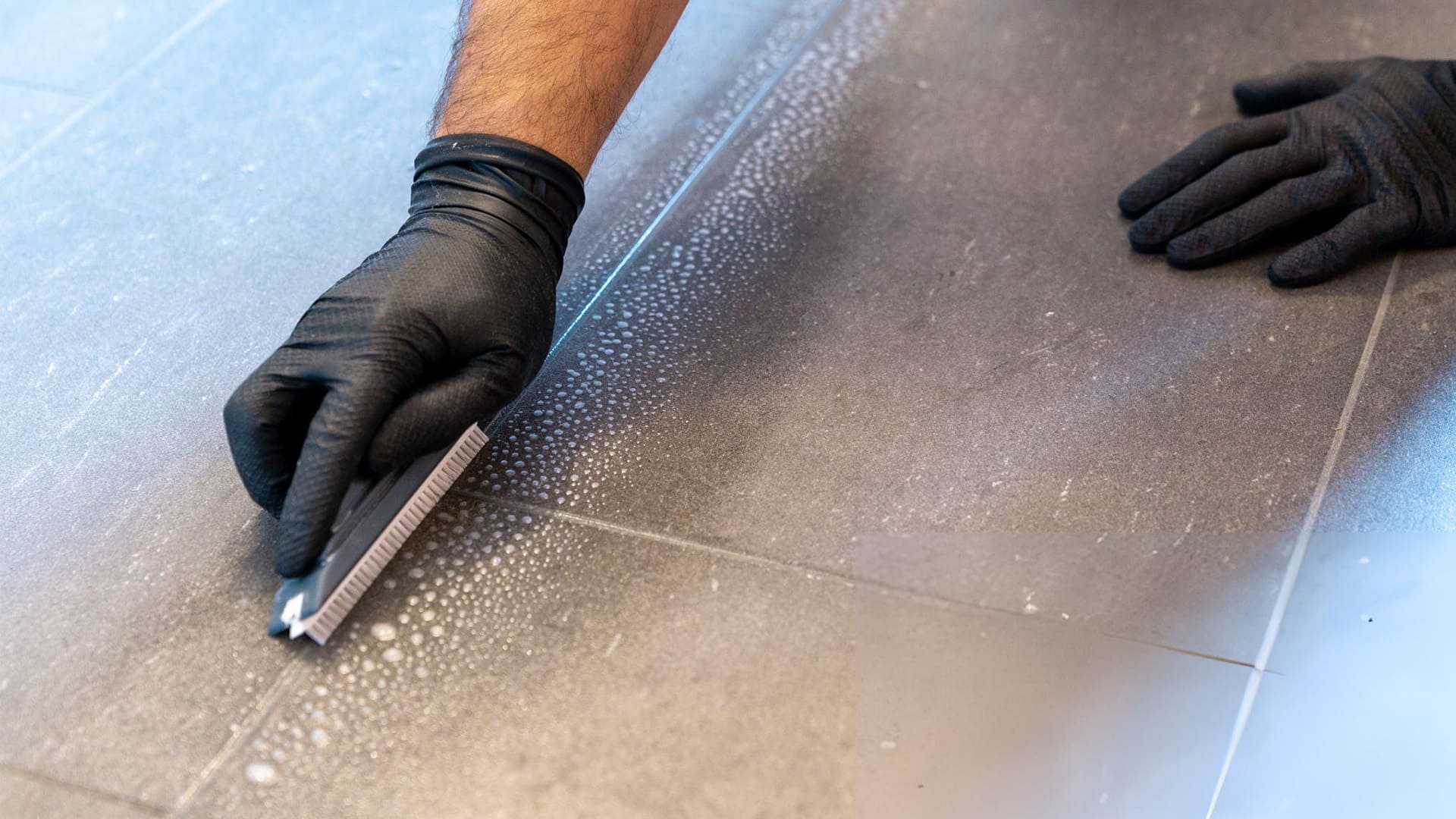 a man is cleaning grout with a special brush
