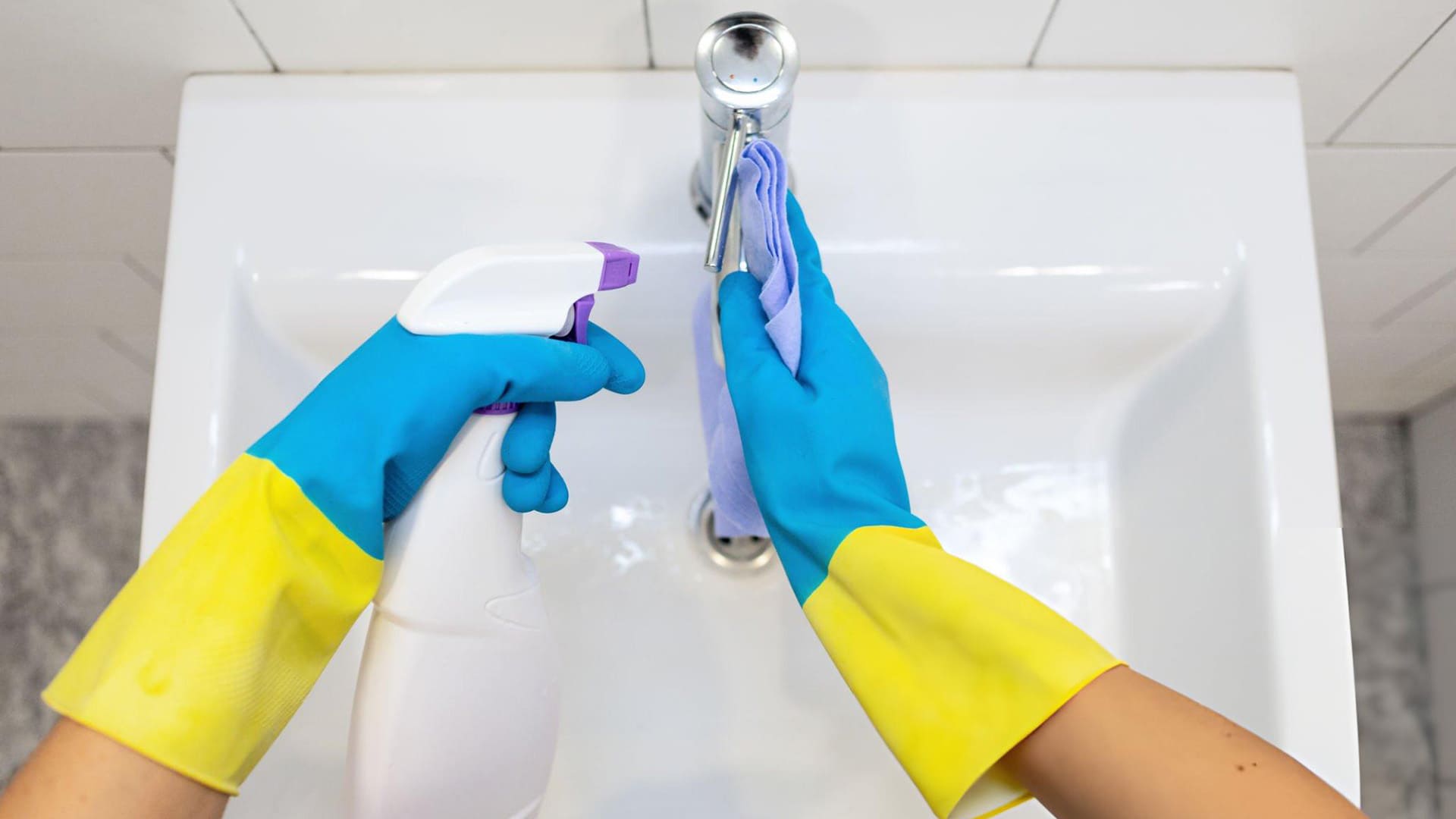 a person wearing a pair of gloves cleaning the faucet
